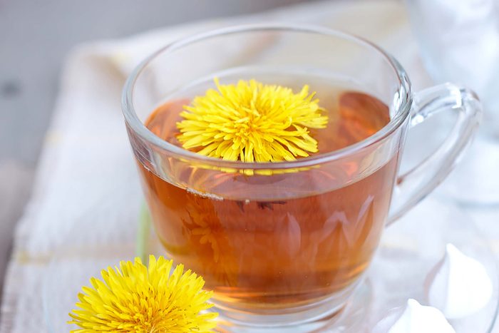 Glass cup of dandelion tea with blossom