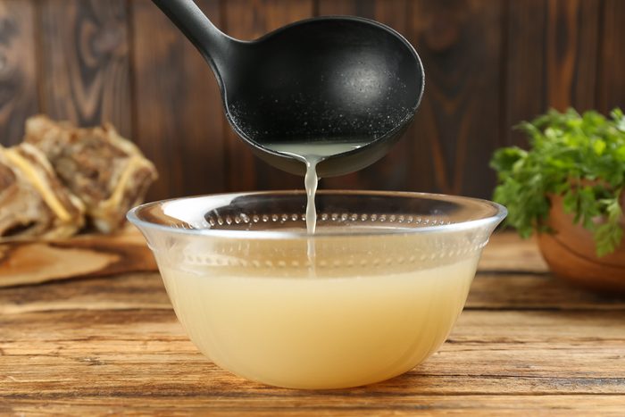 Pouring homemade broth in a large glass bowl