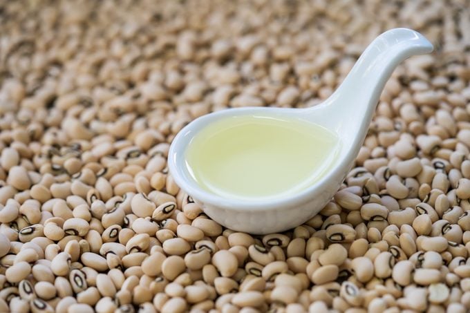 close up of soybean oil in ladle on top of soybeans