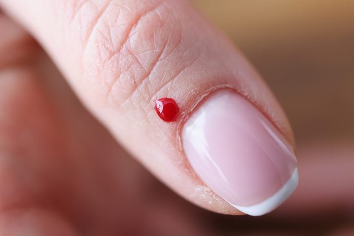 Closeup of drop of blood near woman's nail