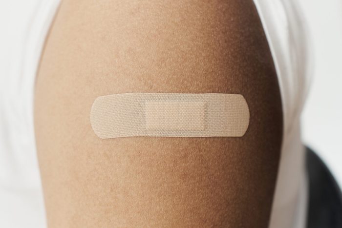 adhesive bandage on the arm of a Black man after receiving the COVID-19 vaccine.