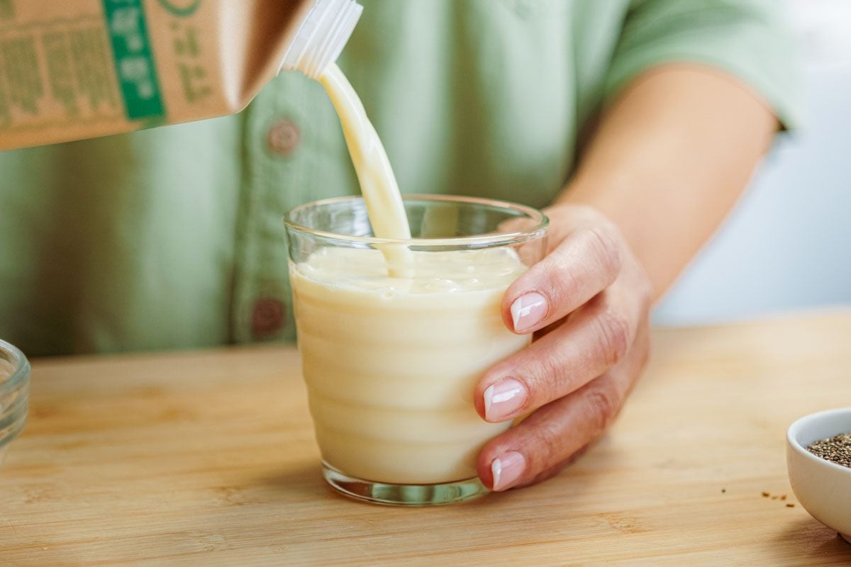 Woman Pouring Soy Milk Into A Glass