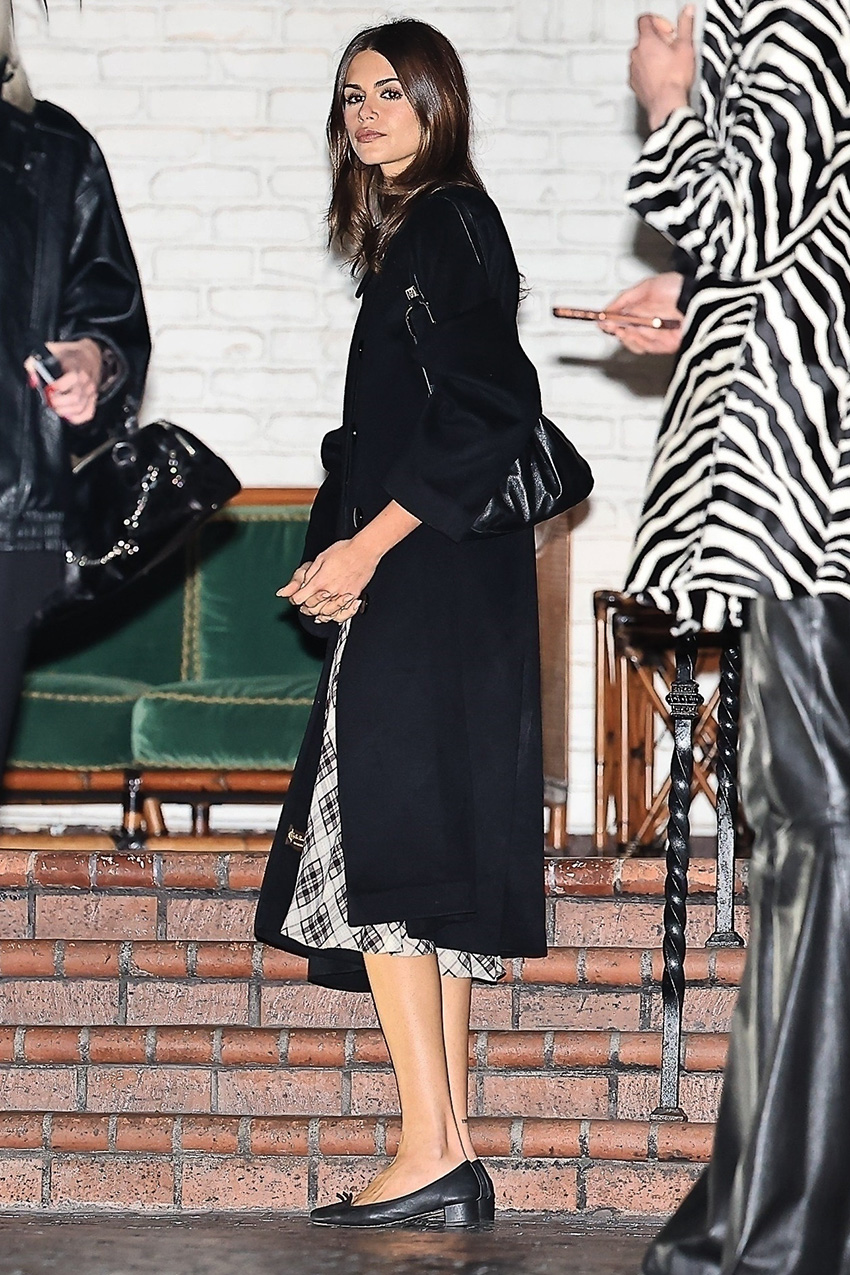 Kaia Gerber wearing a black coat, checked midi skirt, and ballet pumps in L.A.
