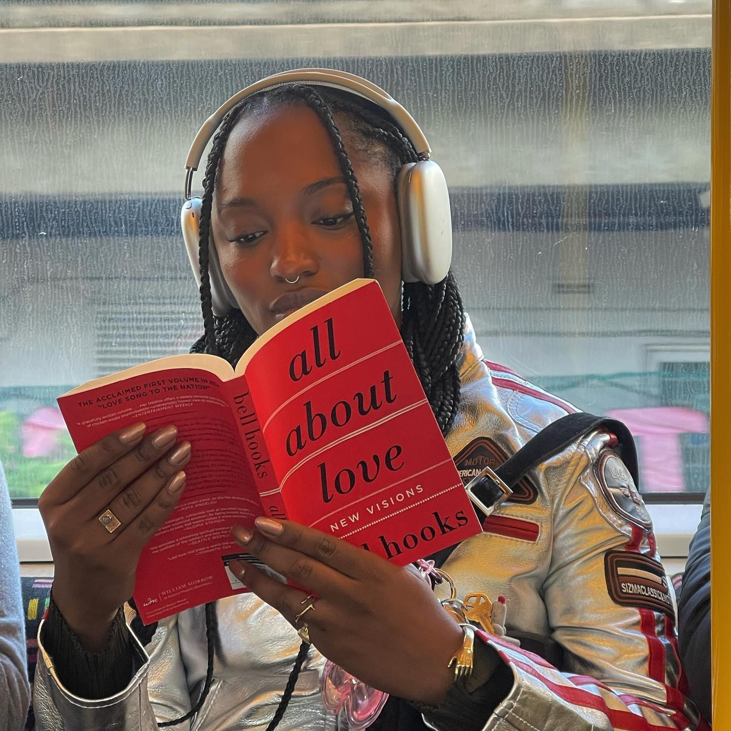 An image of a person wearing headphones and reading a book titled "All About Love."