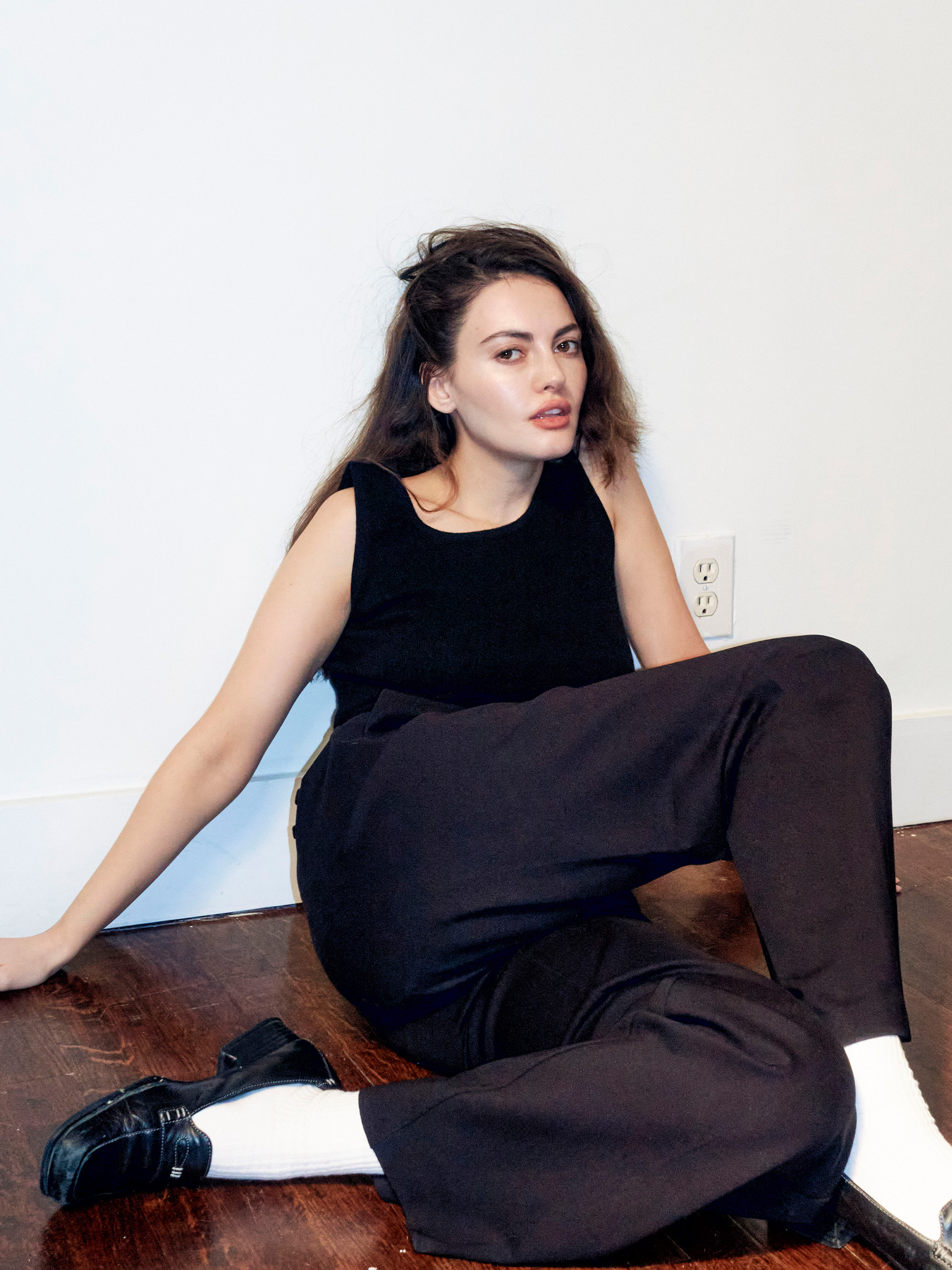 Actress Trew Mullen shot by Ariel Sadok. Mullen is wearing a black tank top and navy trousers with white socks and black loafers.