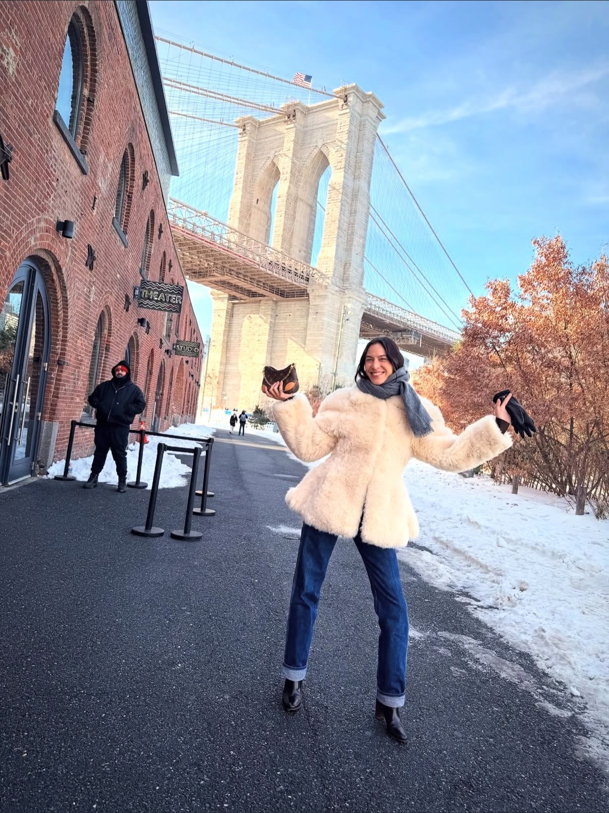 Alexa Chung wears a white fur coat, cuffed jeans, and black ankle boots.