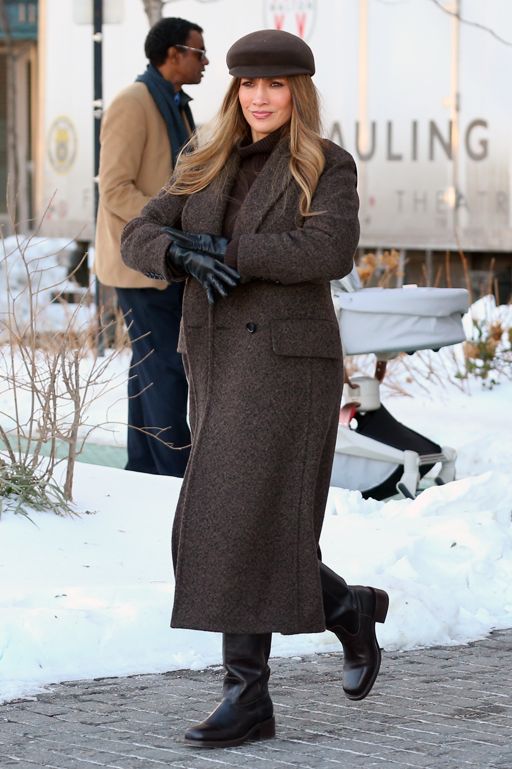Jennifer Lopez wearing a brown coat, brown hat, black gloves, and black boots