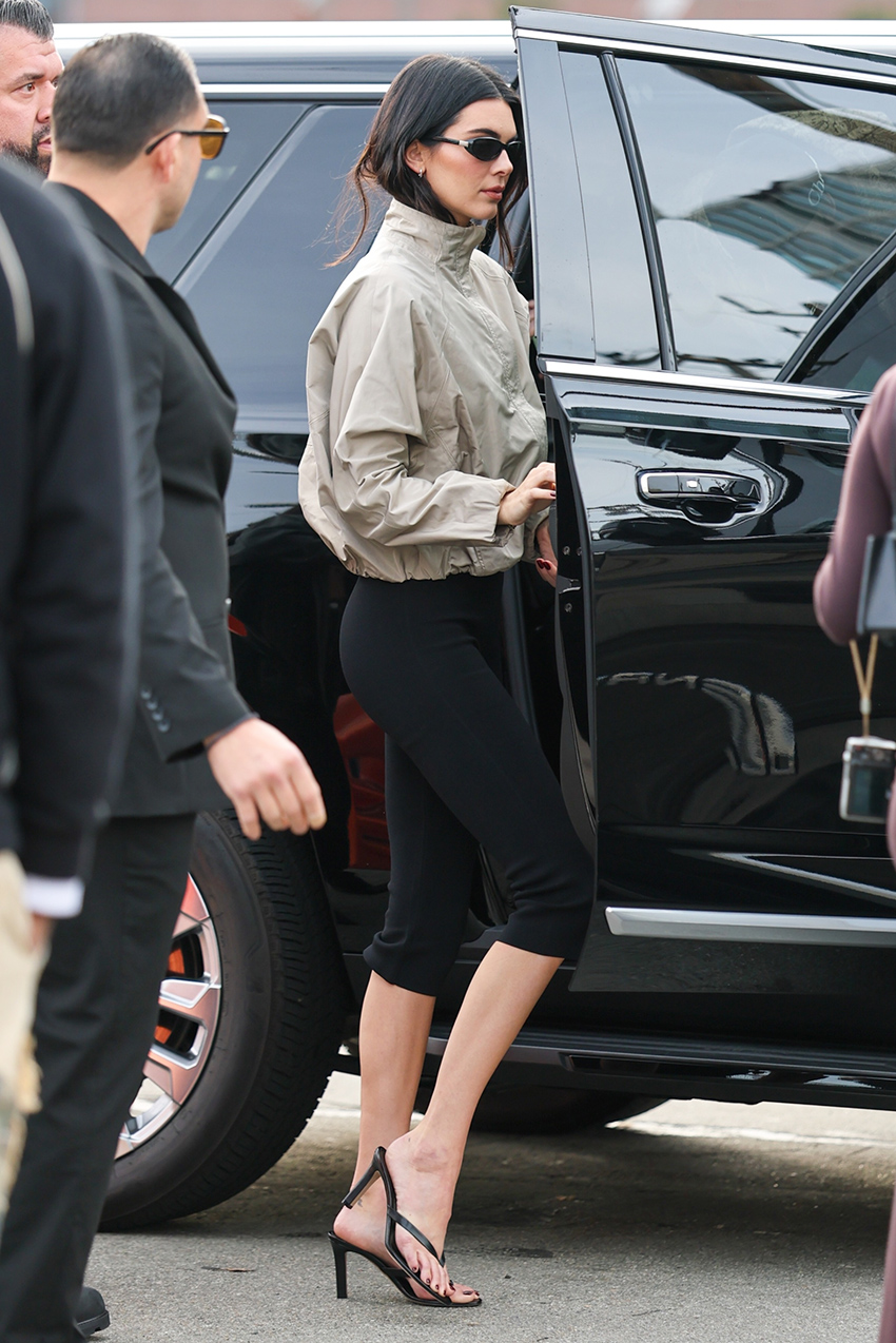 Kendall Jenner wearing a funnel-neck jacket and capri pants with high-heel thong sandals at the Super Bowl in 2026