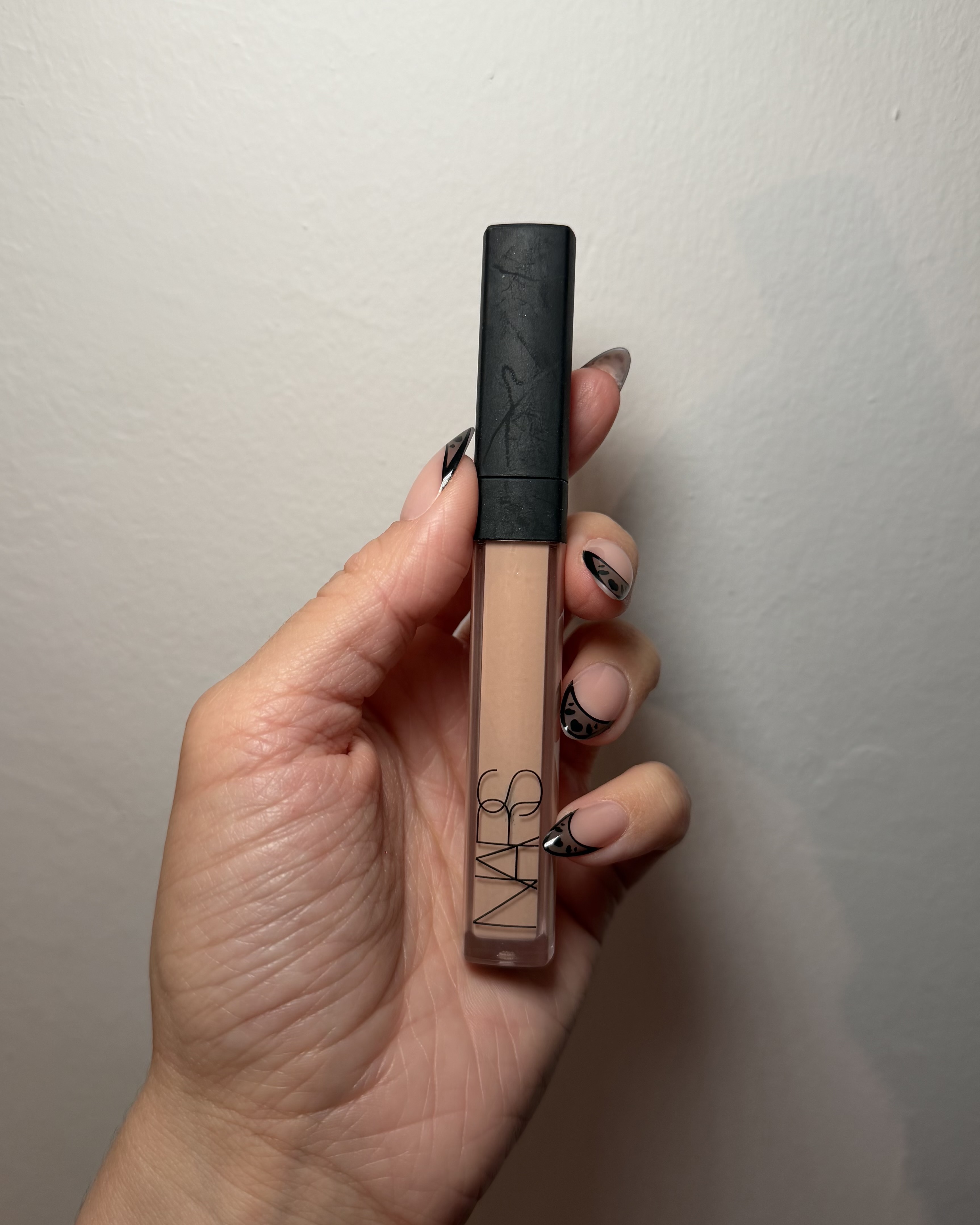An image of Who What Wear associate beauty editor Alyssa Brascia wearing and holding the Nars Radiant Creamy Concealer.
