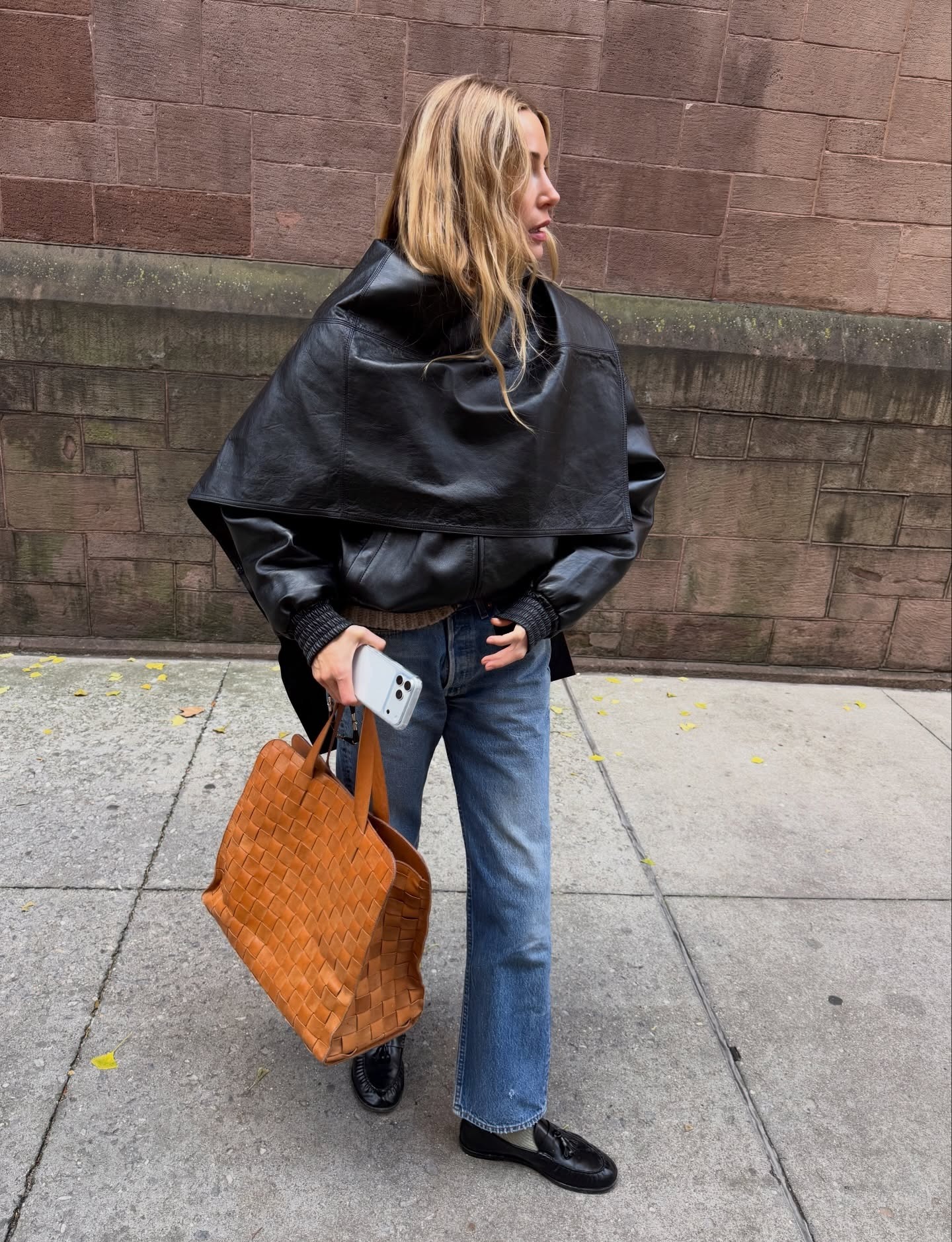 Influencer wearing jeans, a wrap leather jacket, and loafers.