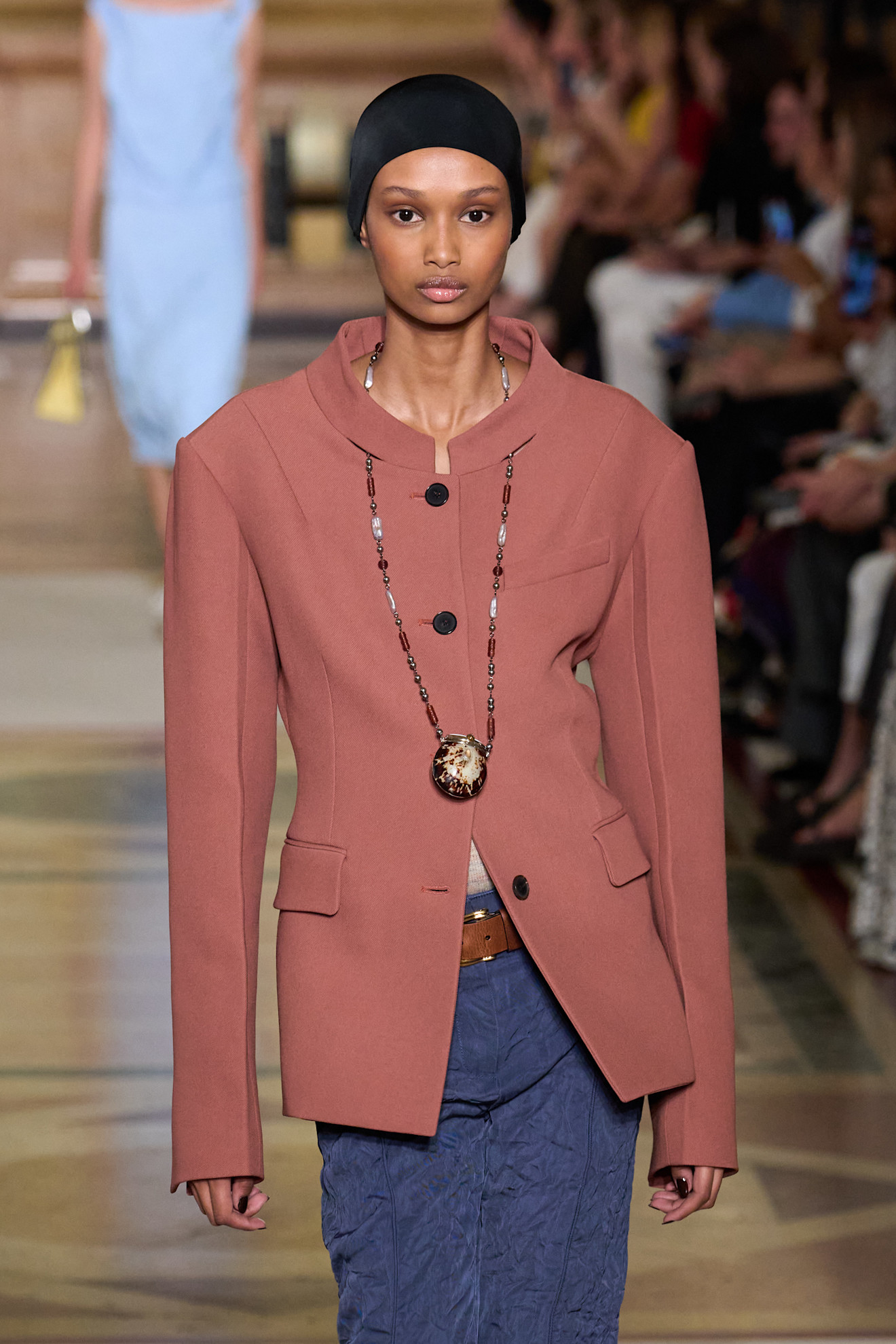 a woman wearing a blazer with a pendant necklace