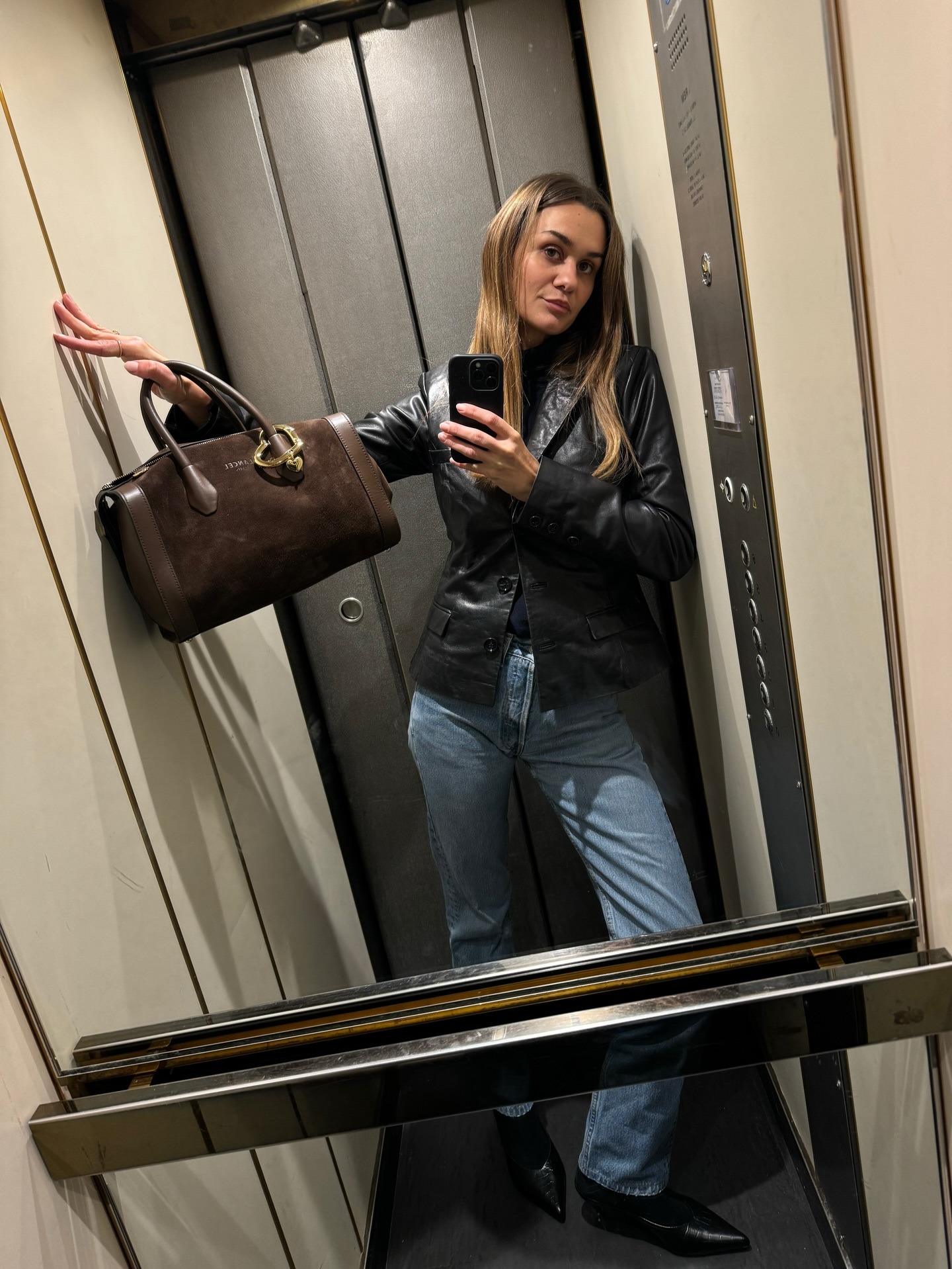 @annelauremais wearing a black leather blazer, black sweater, light-wash jeans, and black boots.